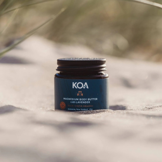 KOA magnesium body butter jar on a textured surface with blurred natural background