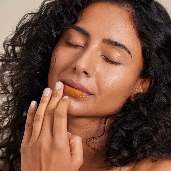 Woman applying a product to her lips with a close-up focus on her face.