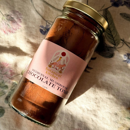 Jar of medicinal mushroom chocolate tonic with a pink label on a floral fabric background